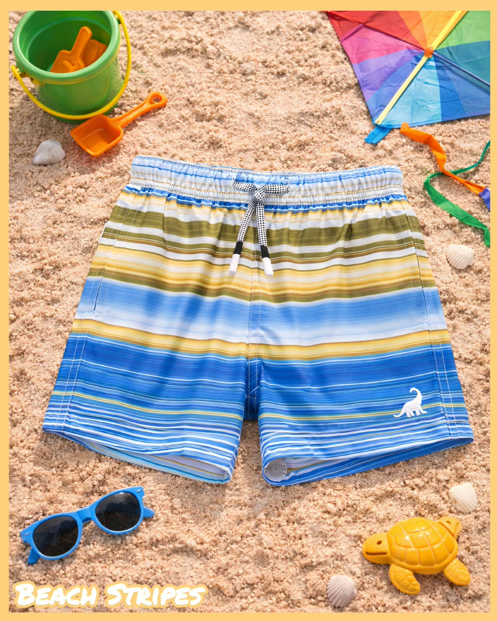 Blue and yellow striped kids swim trunks laid out with beach toys